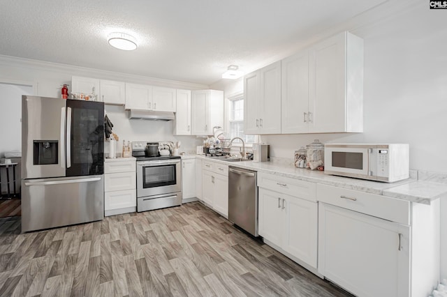 kitchen with sink, light wood-type flooring, a textured ceiling, white cabinetry, and stainless steel appliances