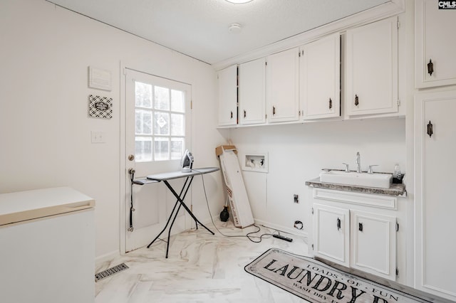 laundry area with hookup for a washing machine, sink, hookup for an electric dryer, a textured ceiling, and cabinets