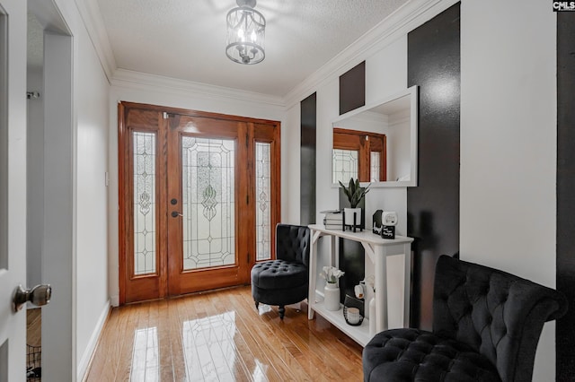 foyer entrance featuring ornamental molding, light hardwood / wood-style flooring, and a textured ceiling