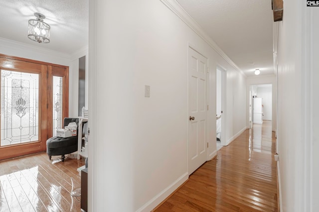 foyer entrance featuring ornamental molding, a textured ceiling, a chandelier, and light wood-type flooring