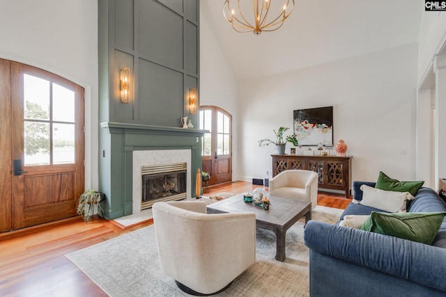 living room with high vaulted ceiling, a chandelier, and light hardwood / wood-style floors