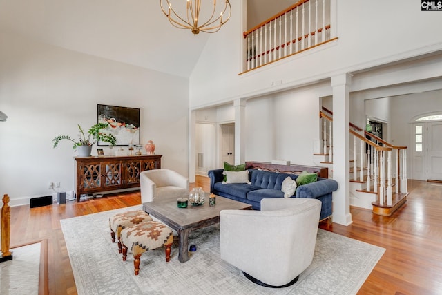 living room featuring a towering ceiling, a notable chandelier, and light hardwood / wood-style floors