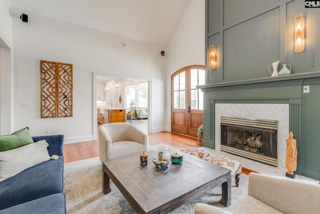 living room with sink, a fireplace, high vaulted ceiling, and light hardwood / wood-style flooring