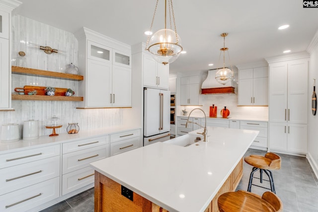 kitchen featuring sink, a breakfast bar, a kitchen island with sink, high end white refrigerator, and white cabinets