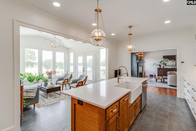 kitchen featuring pendant lighting, sink, crown molding, a center island with sink, and french doors