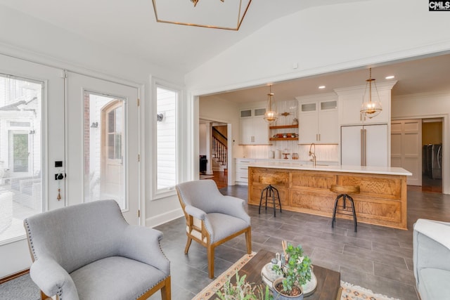 living room with washer / clothes dryer, crown molding, lofted ceiling, and sink