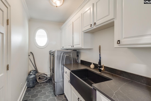 laundry area featuring sink, crown molding, cabinets, washer and dryer, and dark tile patterned flooring