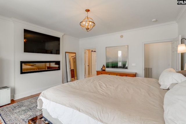 bedroom featuring ornamental molding, wood-type flooring, and a notable chandelier