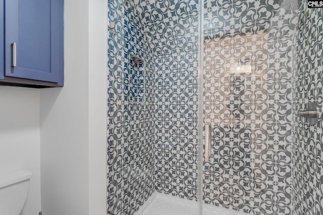 bathroom with a tile shower and toilet