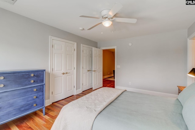 bedroom featuring multiple closets, ceiling fan, and wood-type flooring