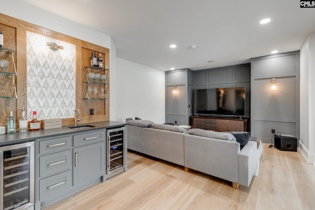 living room featuring indoor wet bar, beverage cooler, and light wood-type flooring