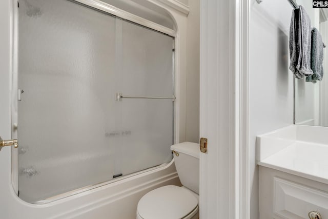 full bathroom with enclosed tub / shower combo, vanity, and toilet