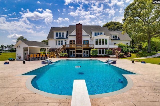 view of swimming pool featuring an outdoor bar, a patio, a diving board, an outbuilding, and pool water feature