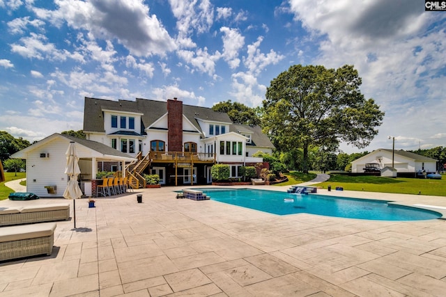 view of swimming pool with a patio, a wooden deck, a lawn, and a bar