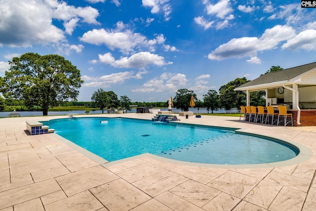 view of pool with an outdoor bar and a patio