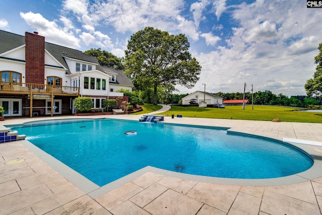 view of swimming pool featuring a patio, a lawn, a deck, and french doors