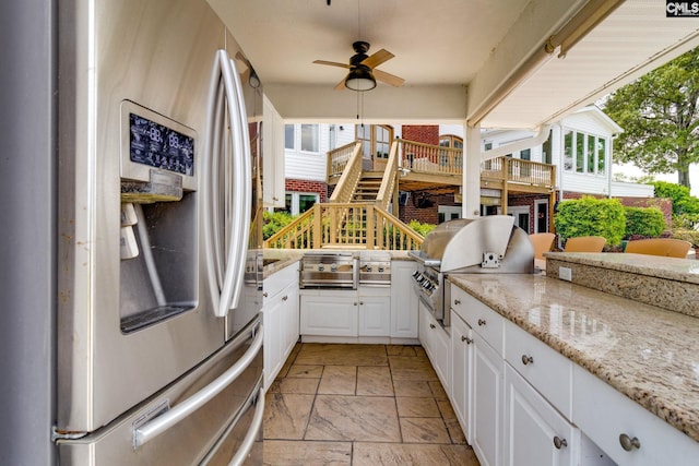 exterior space with ceiling fan, light stone countertops, stainless steel fridge with ice dispenser, and white cabinets