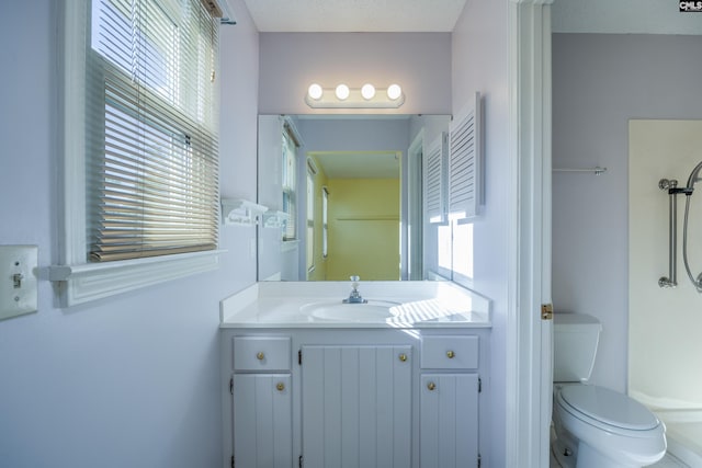 bathroom with vanity, toilet, and a healthy amount of sunlight