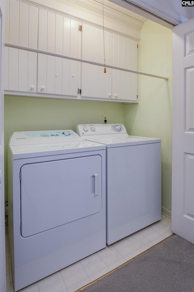 laundry area with light tile patterned floors, separate washer and dryer, and cabinets