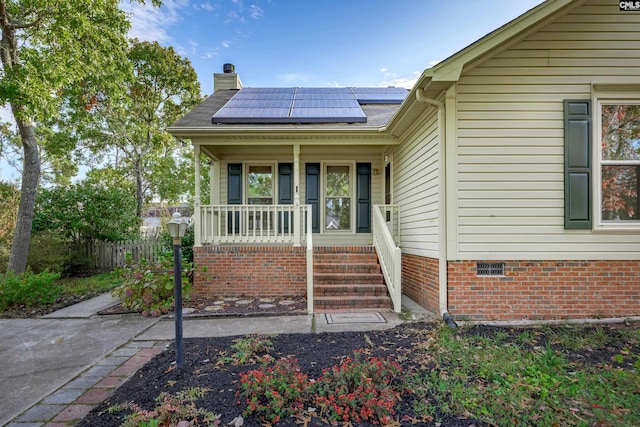 entrance to property featuring a porch and solar panels