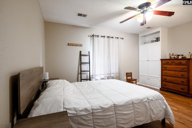 bedroom featuring ceiling fan, a textured ceiling, and light wood-type flooring