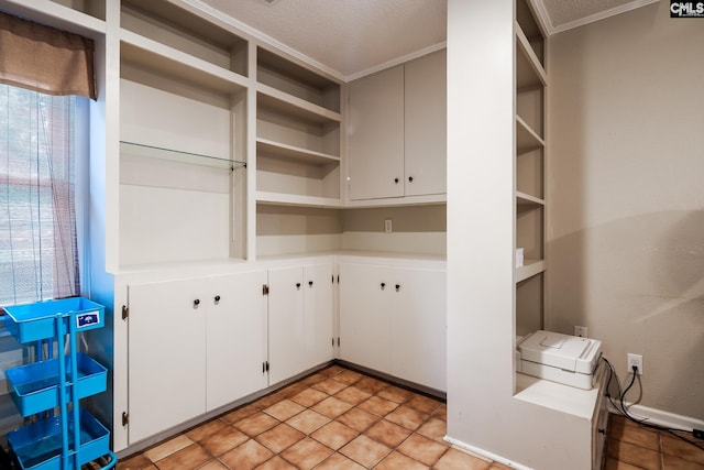 kitchen featuring ornamental molding, white cabinets, a healthy amount of sunlight, and a textured ceiling