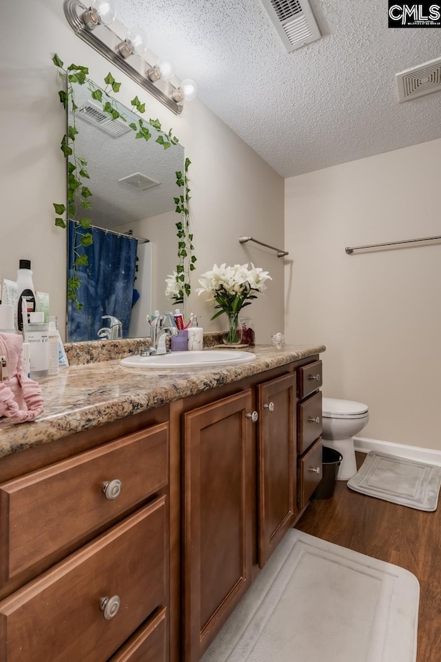 bathroom with a textured ceiling, hardwood / wood-style flooring, toilet, vanity, and a shower with shower curtain