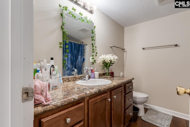 bathroom featuring vanity, hardwood / wood-style floors, a textured ceiling, and toilet