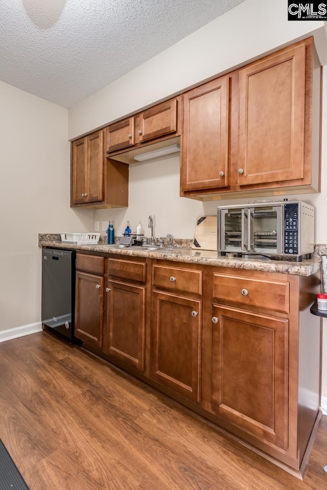 kitchen with dishwasher, a textured ceiling, dark wood-type flooring, and sink