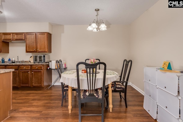 dining room with sink, a notable chandelier, dark hardwood / wood-style floors, and a textured ceiling