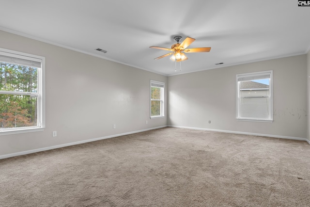 carpeted spare room with ceiling fan, ornamental molding, and a wealth of natural light