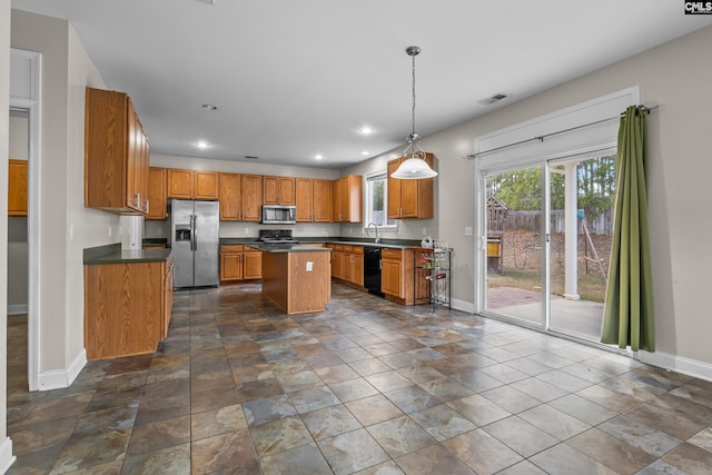 kitchen with appliances with stainless steel finishes, decorative light fixtures, sink, and a kitchen island