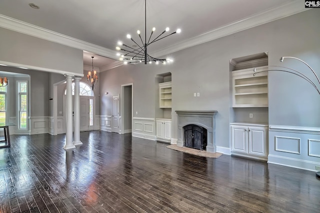 unfurnished living room featuring dark wood-type flooring, crown molding, built in features, and decorative columns