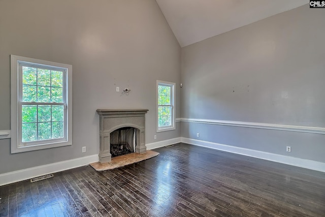 unfurnished living room featuring high vaulted ceiling and dark wood-type flooring