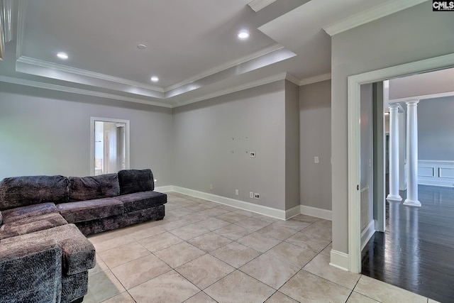 living room with decorative columns, a raised ceiling, ornamental molding, and light wood-type flooring