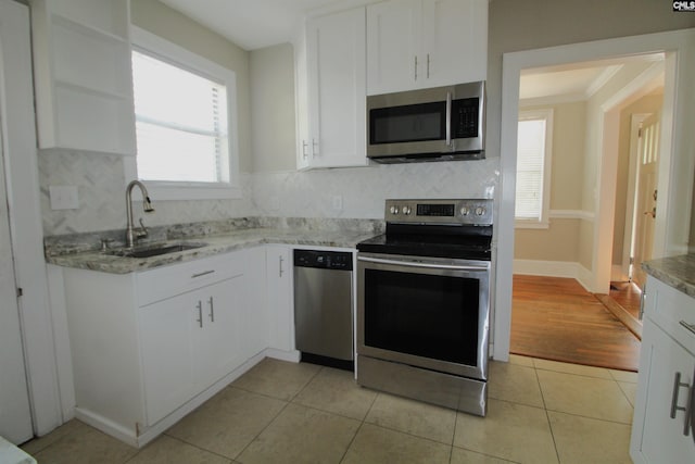 kitchen with appliances with stainless steel finishes, white cabinetry, light hardwood / wood-style flooring, ornamental molding, and sink