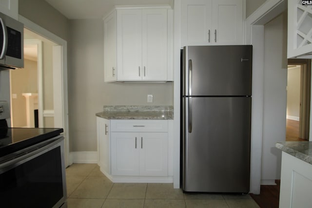 kitchen with white cabinetry, stainless steel appliances, light stone countertops, and light tile patterned floors