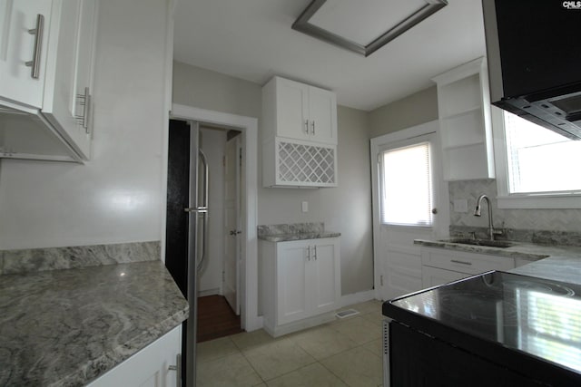 kitchen featuring range with electric cooktop, sink, light tile patterned flooring, white cabinetry, and stainless steel refrigerator