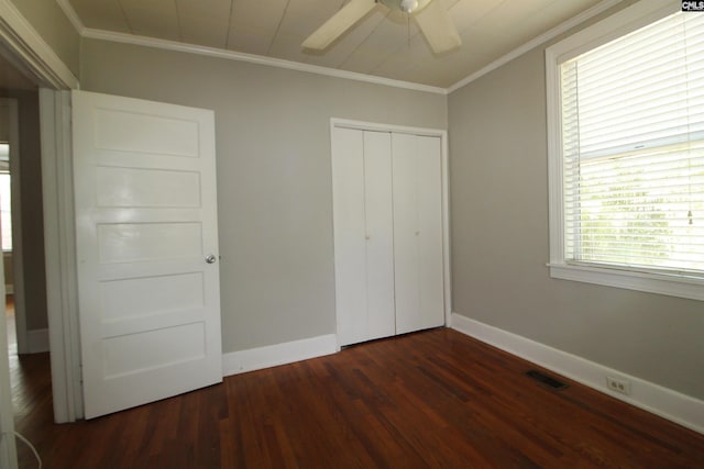 unfurnished bedroom featuring a closet, dark wood-type flooring, crown molding, and ceiling fan