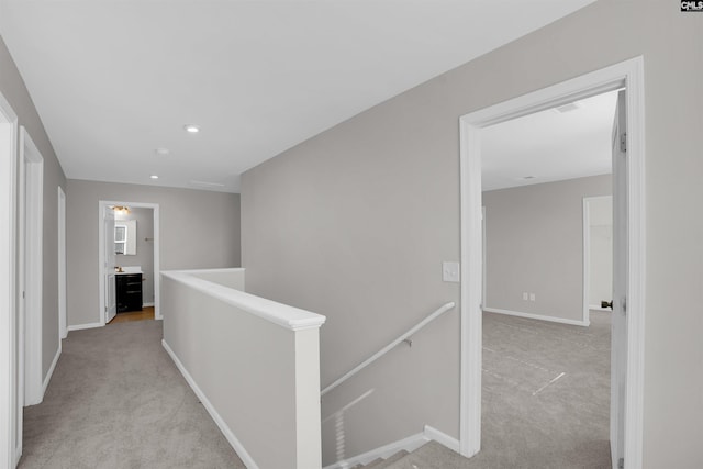 corridor with baseboards, recessed lighting, light carpet, and an upstairs landing