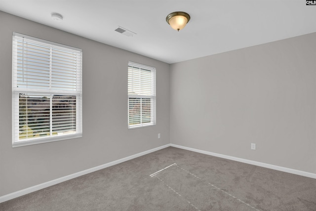 carpeted spare room featuring baseboards and visible vents
