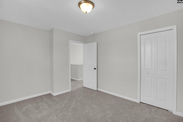 unfurnished bedroom featuring light carpet and a closet