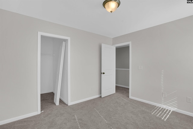 unfurnished bedroom with a spacious closet, a closet, and light colored carpet