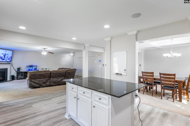 kitchen with ceiling fan with notable chandelier, a kitchen island, light hardwood / wood-style floors, decorative light fixtures, and white cabinets