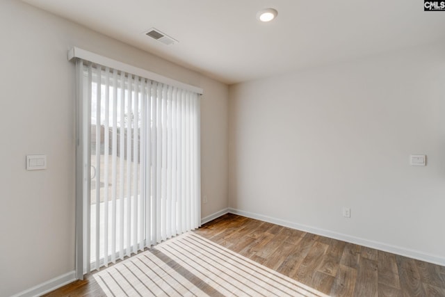 empty room with hardwood / wood-style flooring and plenty of natural light