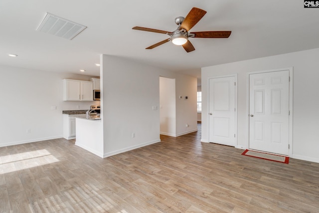 unfurnished living room with light wood-type flooring and ceiling fan