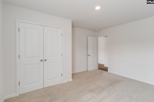 unfurnished bedroom featuring light colored carpet and a closet