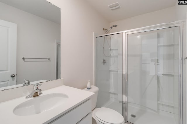 bathroom featuring toilet, a shower with shower door, and vanity