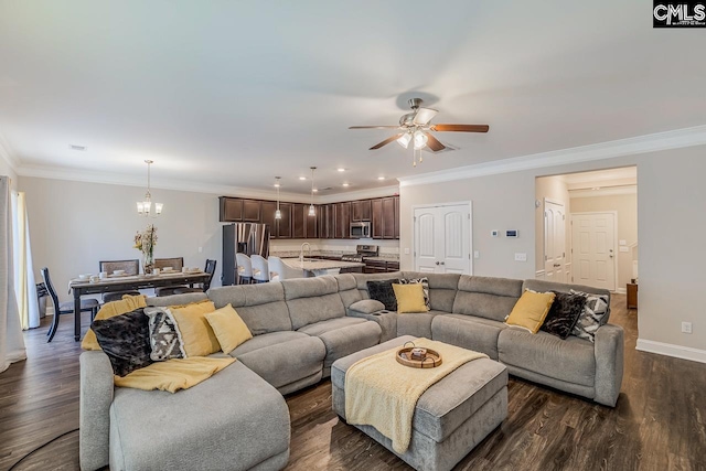 living room with dark wood-type flooring, ornamental molding, sink, and ceiling fan with notable chandelier