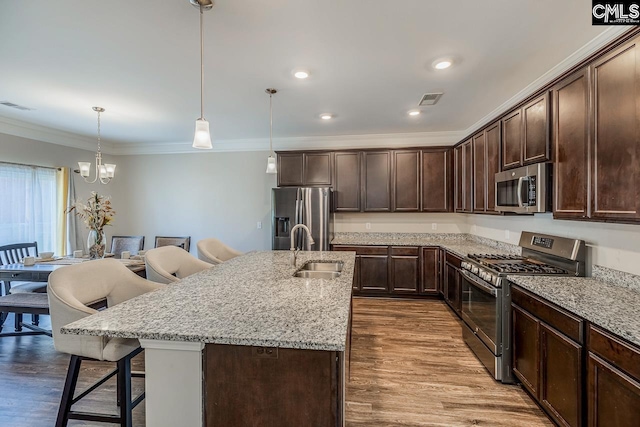 kitchen featuring hanging light fixtures, wood-type flooring, sink, a kitchen bar, and appliances with stainless steel finishes